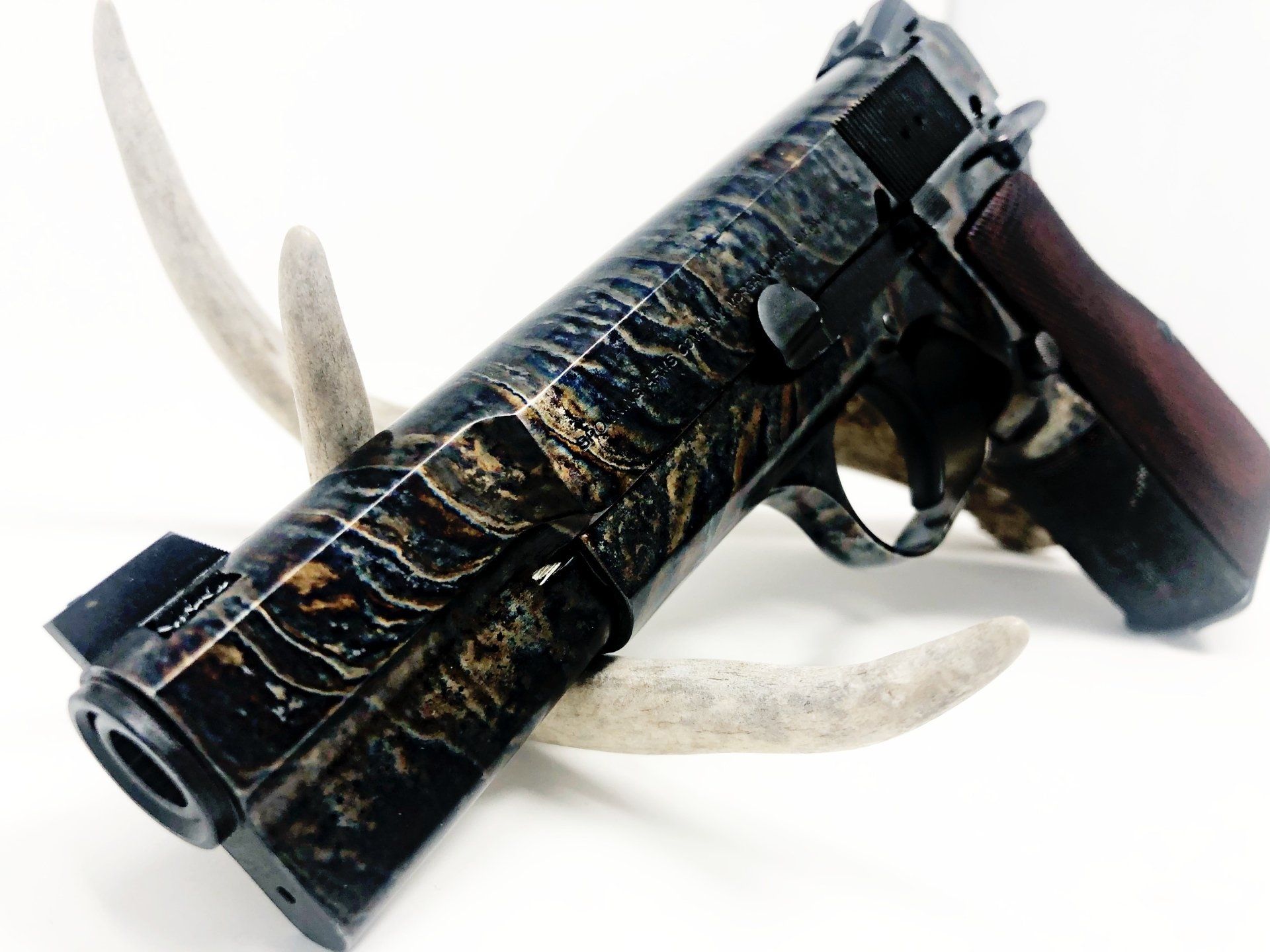 Custom handgun with a marbled finish, set on antler against a white background.