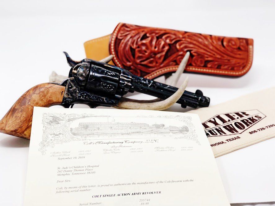 Black gun with carved leather holster, antlers, and document.