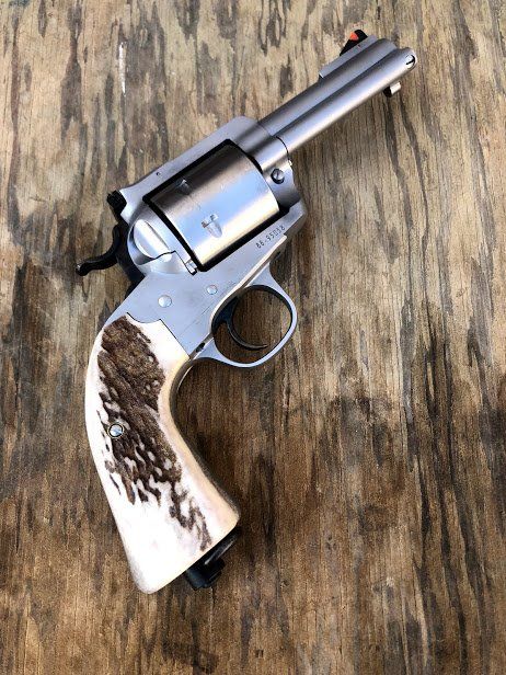 Silver revolver with light-colored antler grip on a wood surface.