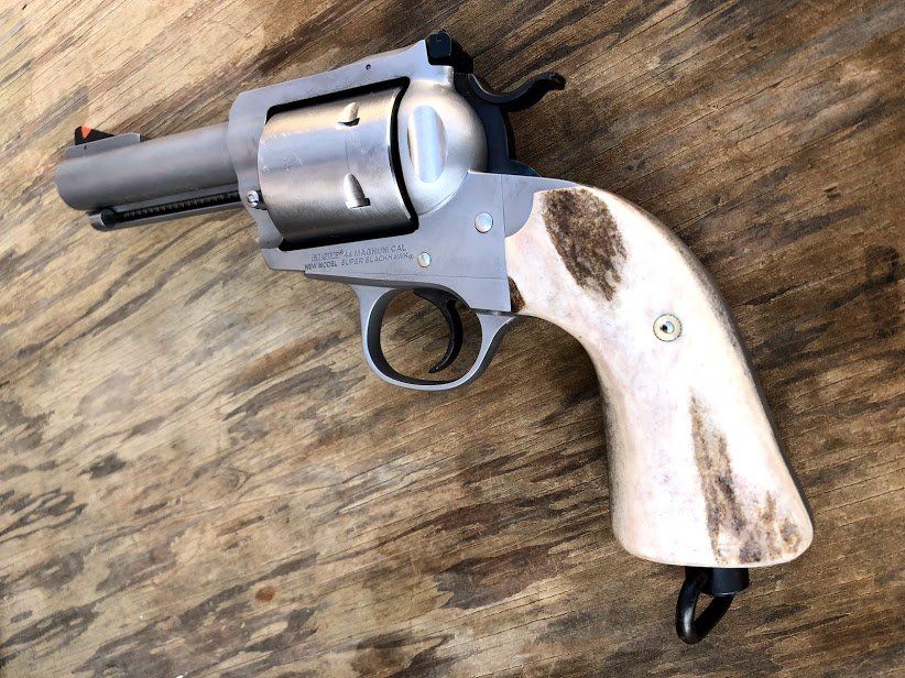 Revolver with light-colored, patterned grips and stainless steel finish, resting on a wooden surface.