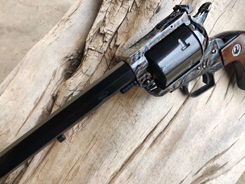 A black and wood-grain revolver resting on a textured wooden surface.