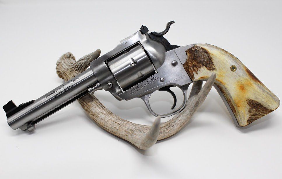 Silver revolver with antler grip rests on a deer antler against a white background.