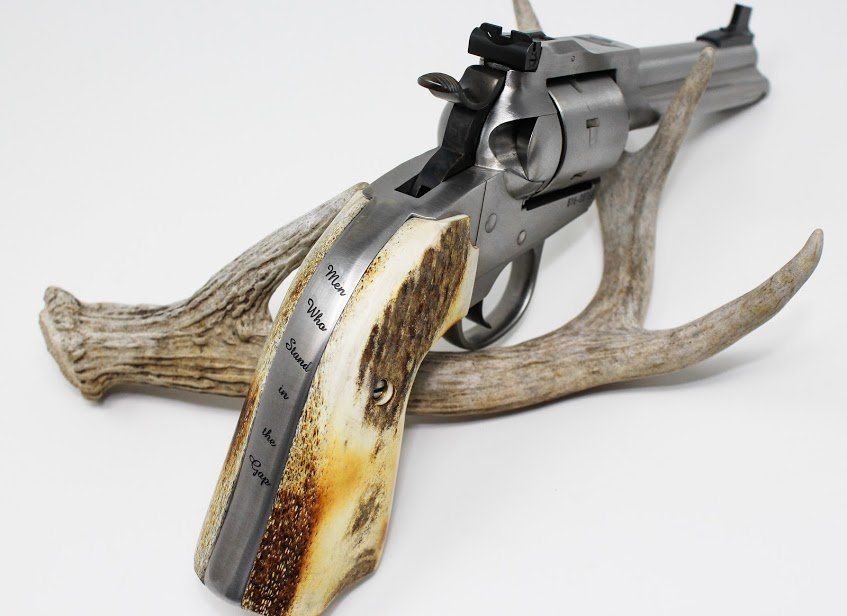 Revolver with antler handle, resting on an antler, on a white surface.