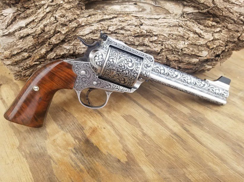 Engraved silver revolver with wooden handle, set against wood and tree bark.