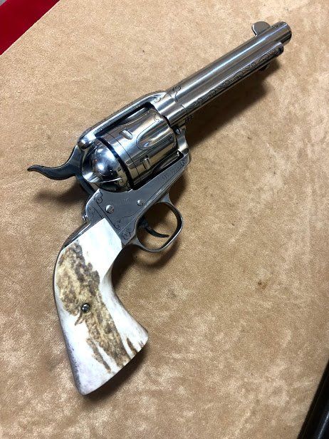 A shiny silver revolver with white and brown antler grips, on a beige surface.
