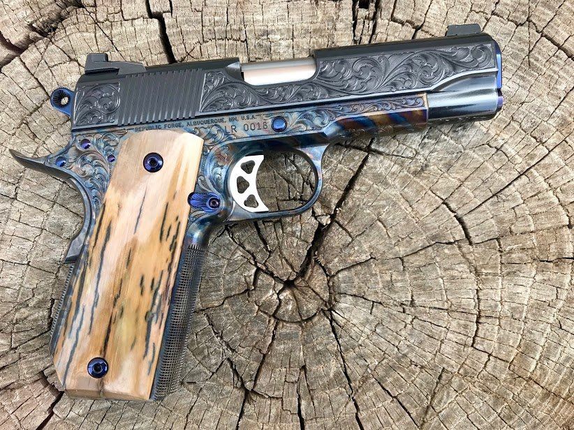 Ornate engraved handgun with wood grips, resting on a weathered wood surface.