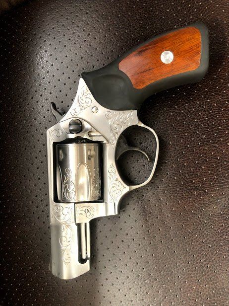Silver revolver with decorative engraving and wooden handle.