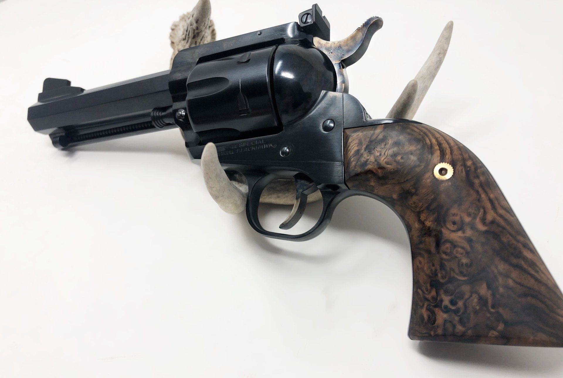Black revolver with wood grain handle resting on white antlers.