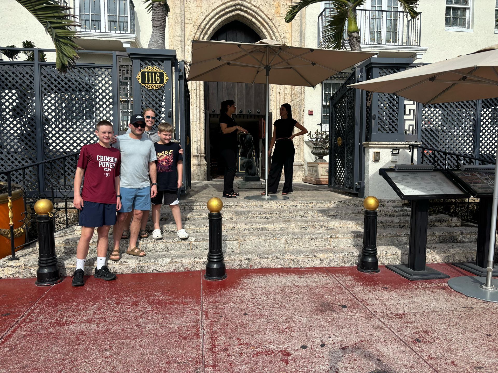 Friendly tour guide assisting guests with photos at the Versace Mansion stop during a Miami City Tour
