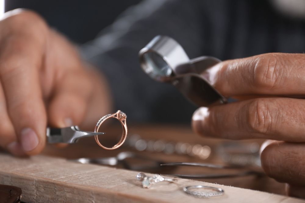 Jeweler Using a Rotary Tool to Work on a Ring With a Green Gemstone — Regency Jewellers in Cairns City, QLD