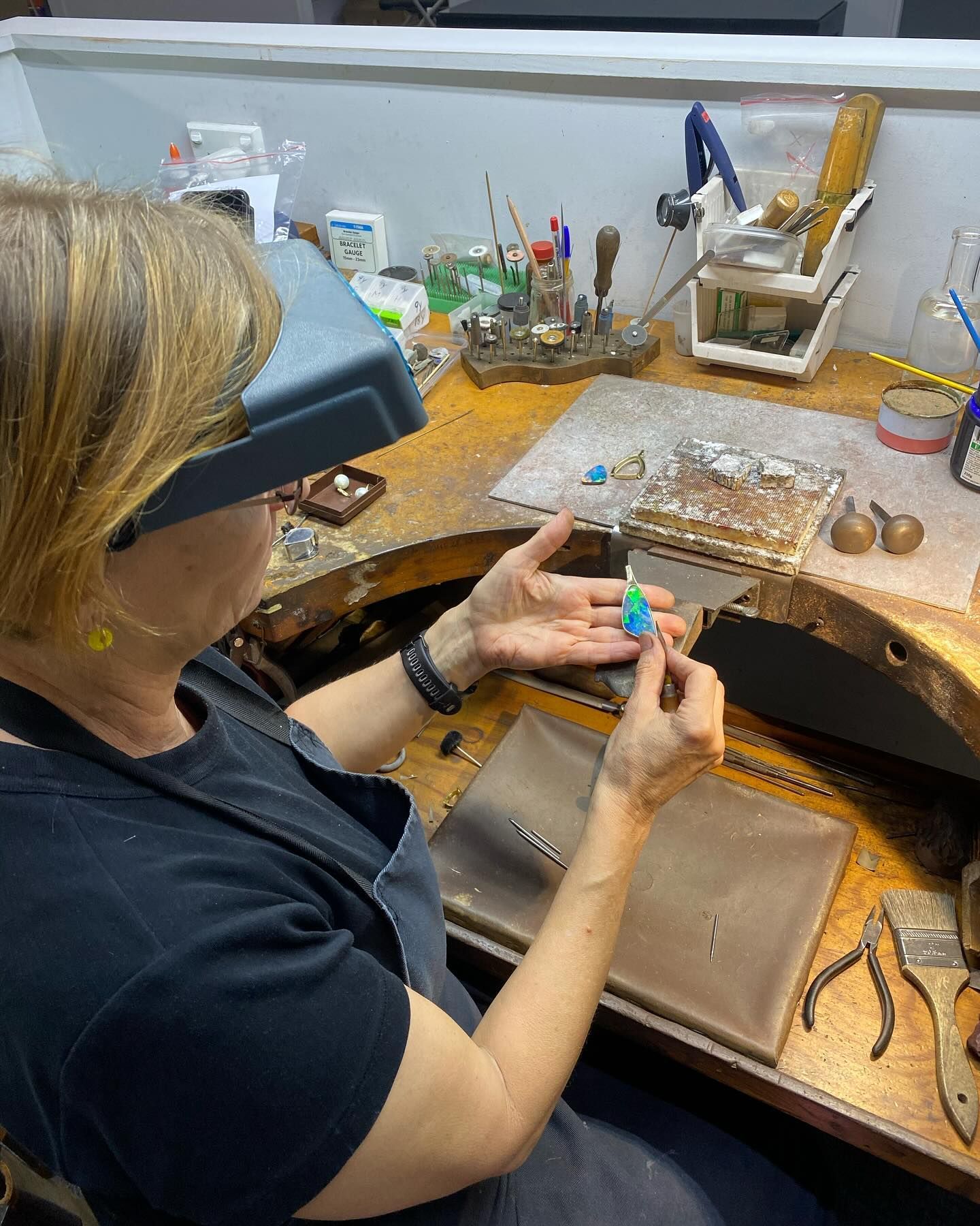 A Person Working at a Jewelry Bench, Examining a Small Blue and Green Object — Regency Jewellers in Cairns City, QLD