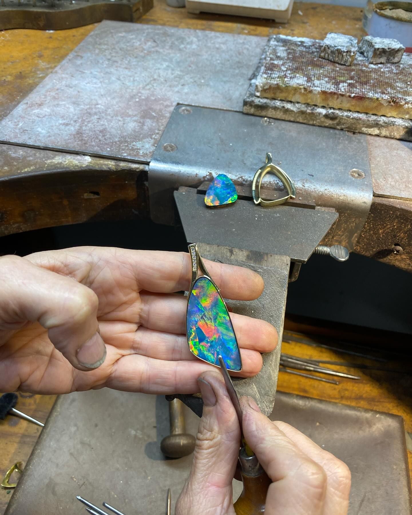 Hands Holding a Pendant With a Colorful Opal, Being Worked on at a Jewelry — Regency Jewellers in Cairns City, QLD