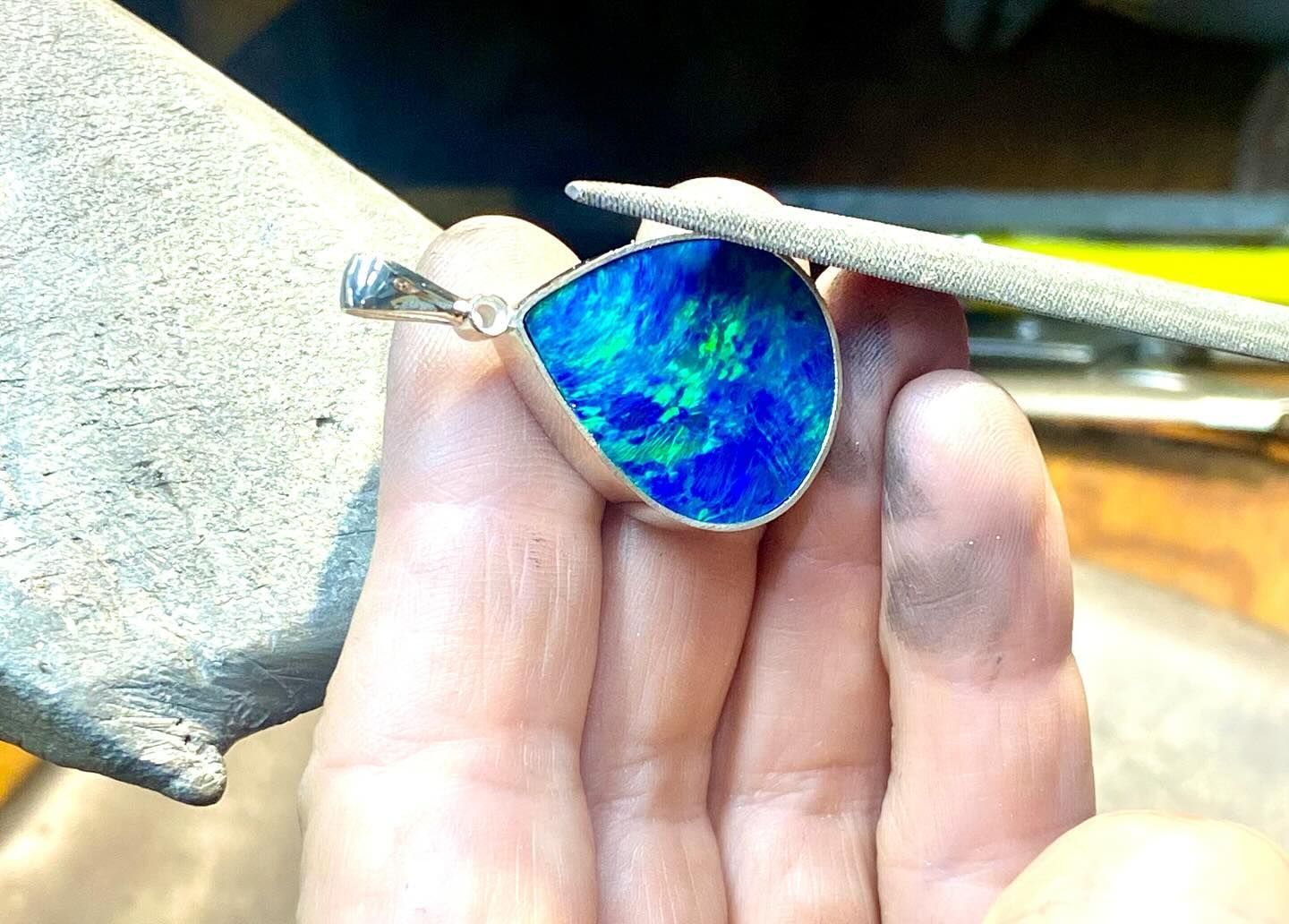 Hand holding a pendant with a blue and green opal, being filed. — Regency Jewellers in Cairns City, QLD