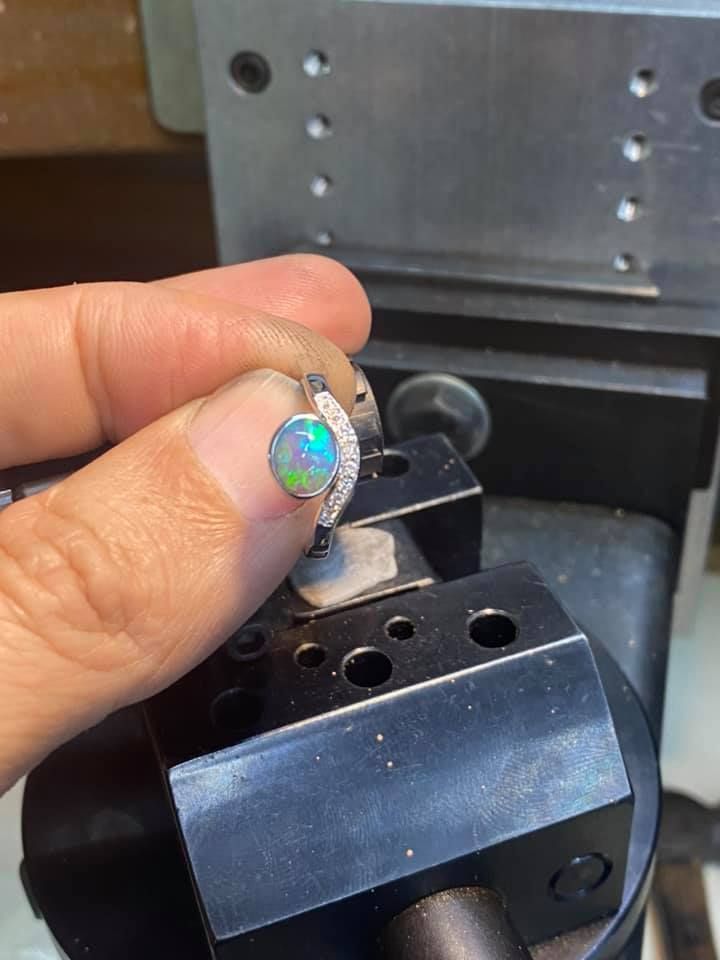 Two Diamond Rings With Green Gemstones on a Dark, Textured Surface — Regency Jewellers in Cairns City, QLD