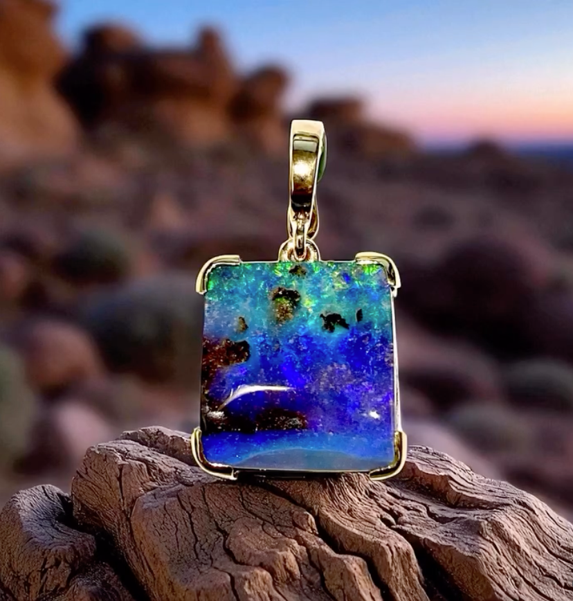 Gold Necklace With a Dark Round Pendant on White Snowy Surface — Regency Jewellers in Cairns City, QLD