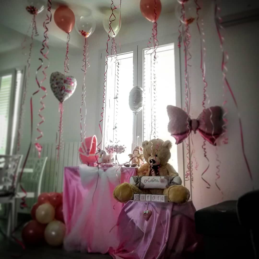 Un orsacchiotto seduto su un tavolo con palloncini appesi al soffitto