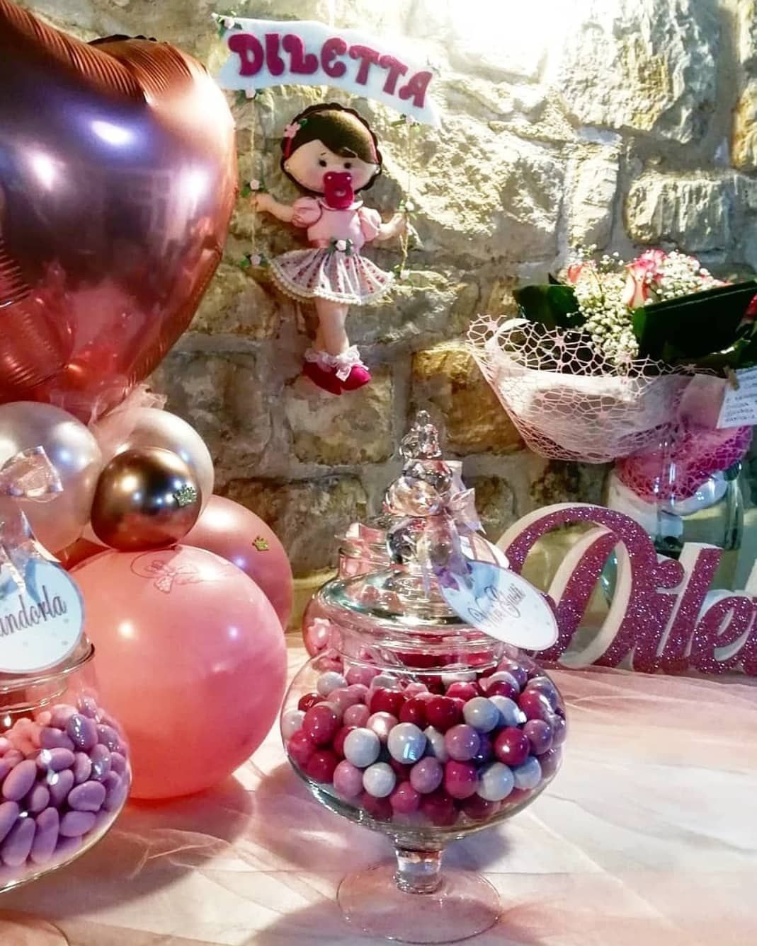 Un tavolo con palloncini, caramelle e una bambola sopra.