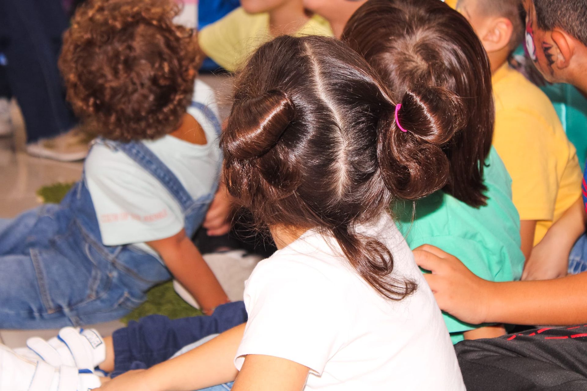 Un gruppo di bambini è seduto sul pavimento e guarda qualcosa