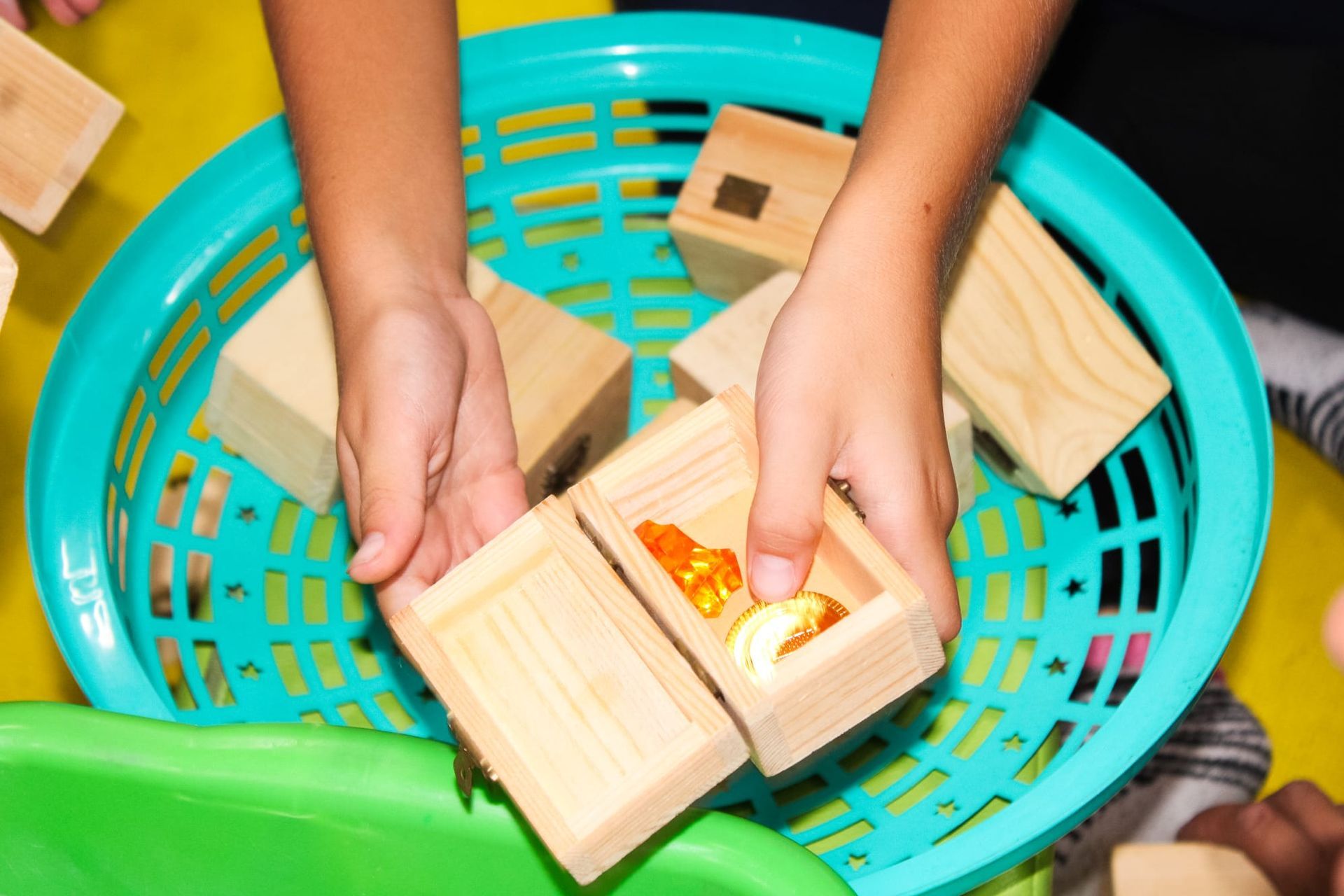 Un bambino sta giocando con blocchi di legno in un cestino blu