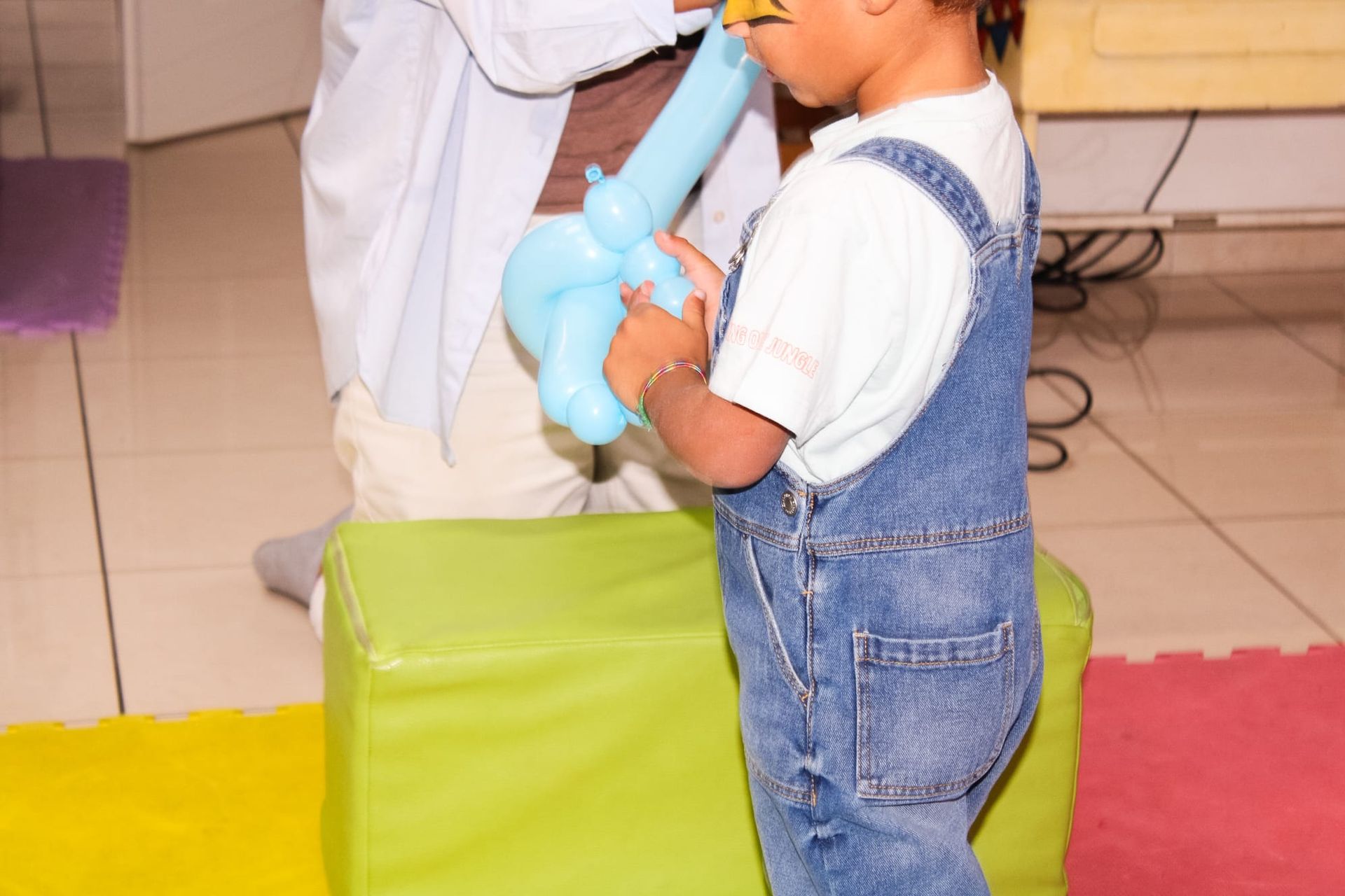 Un ragazzino in tuta sta gonfiando un palloncino blu
