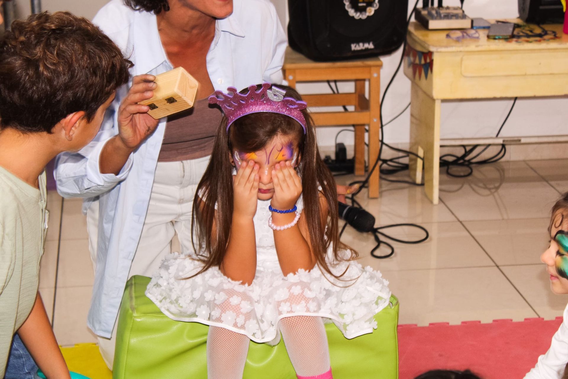 Una bambina si copre gli occhi mentre è seduta su una poltrona a sacco verde