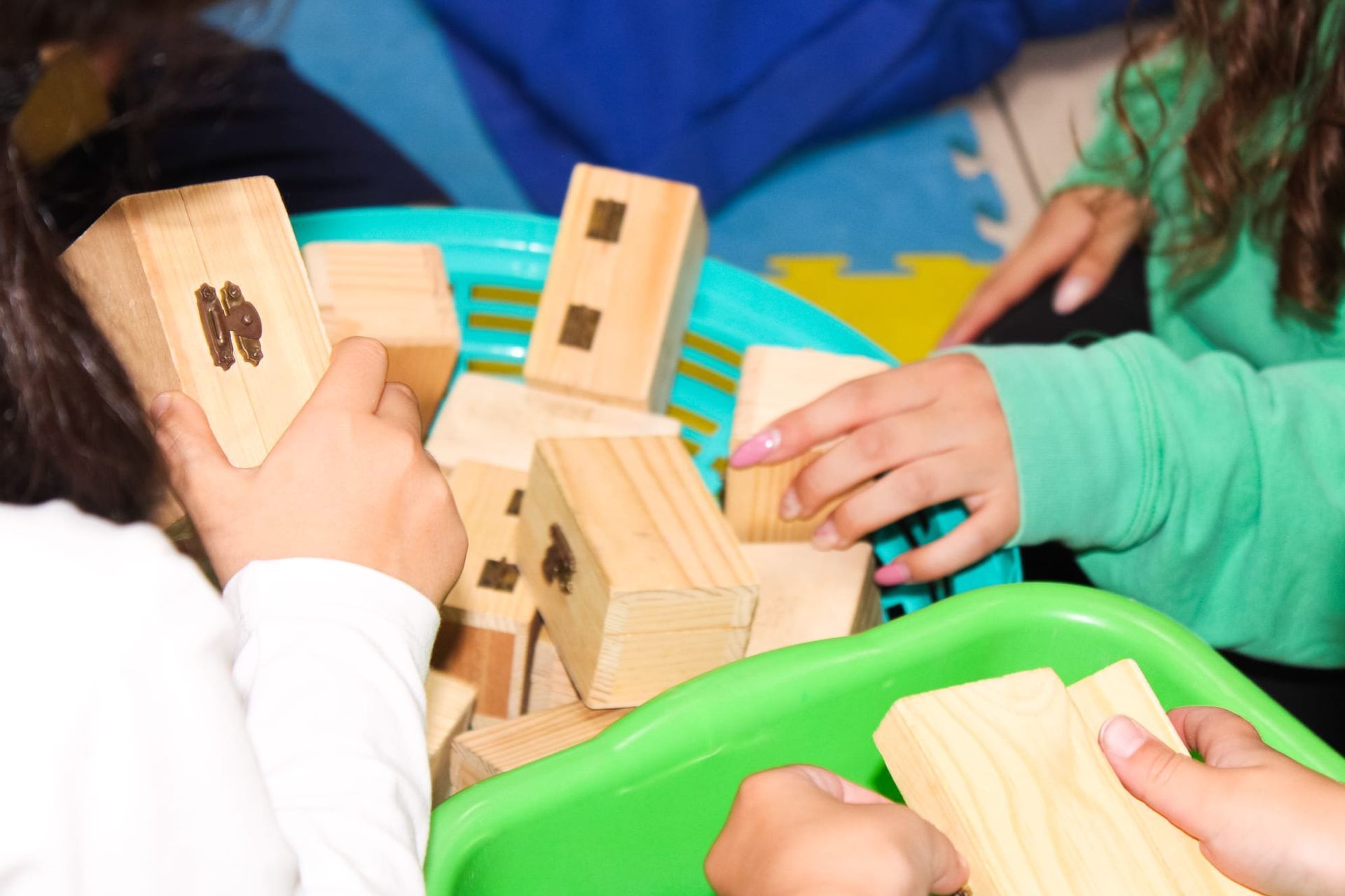 Due bambini stanno giocando con blocchi di legno in un vassoio verde