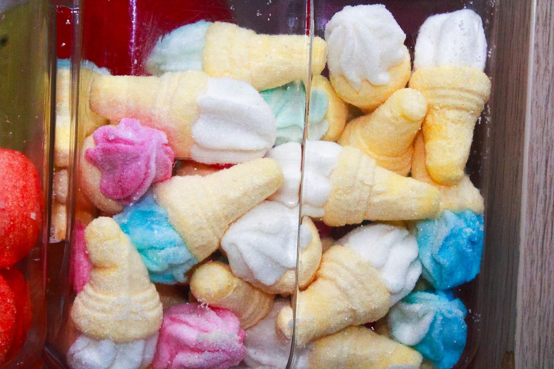 Un contenitore di vetro pieno di marshmallow colorati a forma di cono gelato.