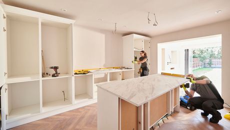 A man and a woman are working on a kitchen.