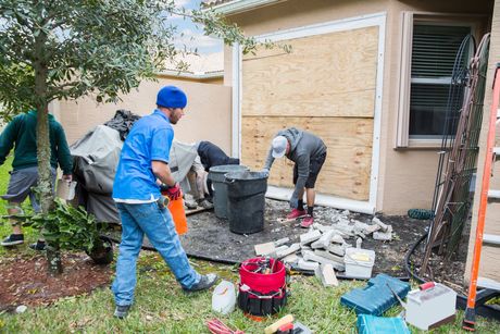 A group of men are working on a house that has been damaged by a hurricane.