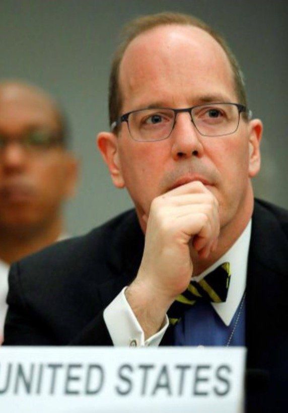 A man sitting in front of a sign that says united states