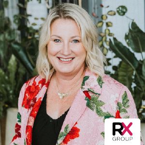 Smiling blonde woman in a pink floral blazer with a RX Group logo in the corner