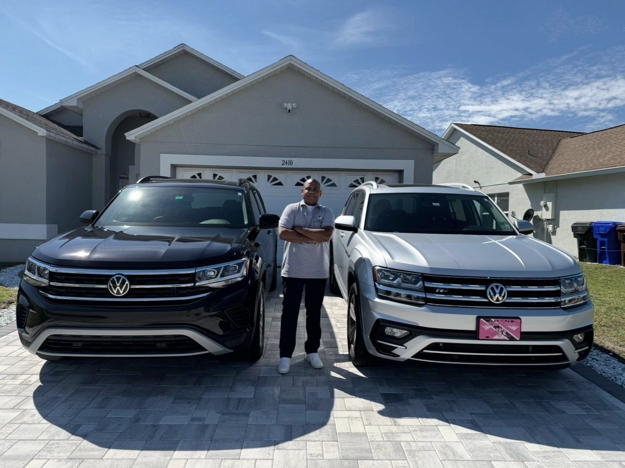 A man is standing in front of two Volkswagen cars