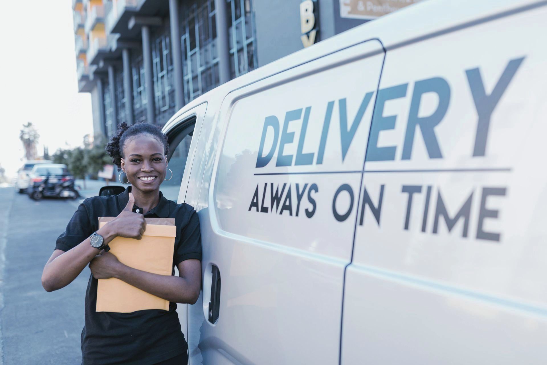 A delivery woman is standing in front of a delivery van