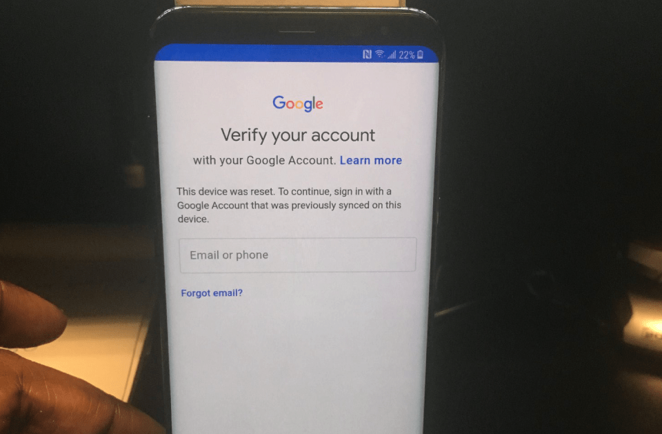 A person is holding a cell phone that says verify your account on the screen.