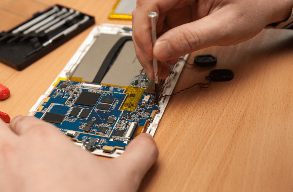 A person is fixing a cell phone with a screwdriver.