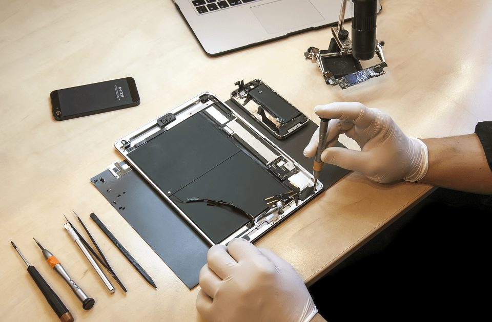 A person is repairing a tablet on a table.