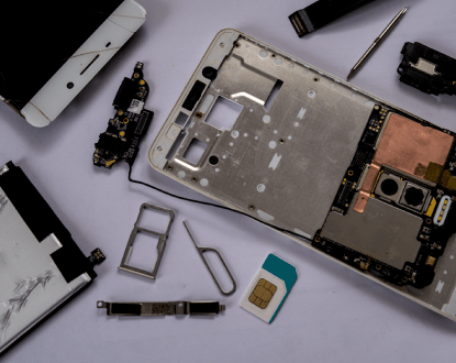 A cell phone is being disassembled on a white surface