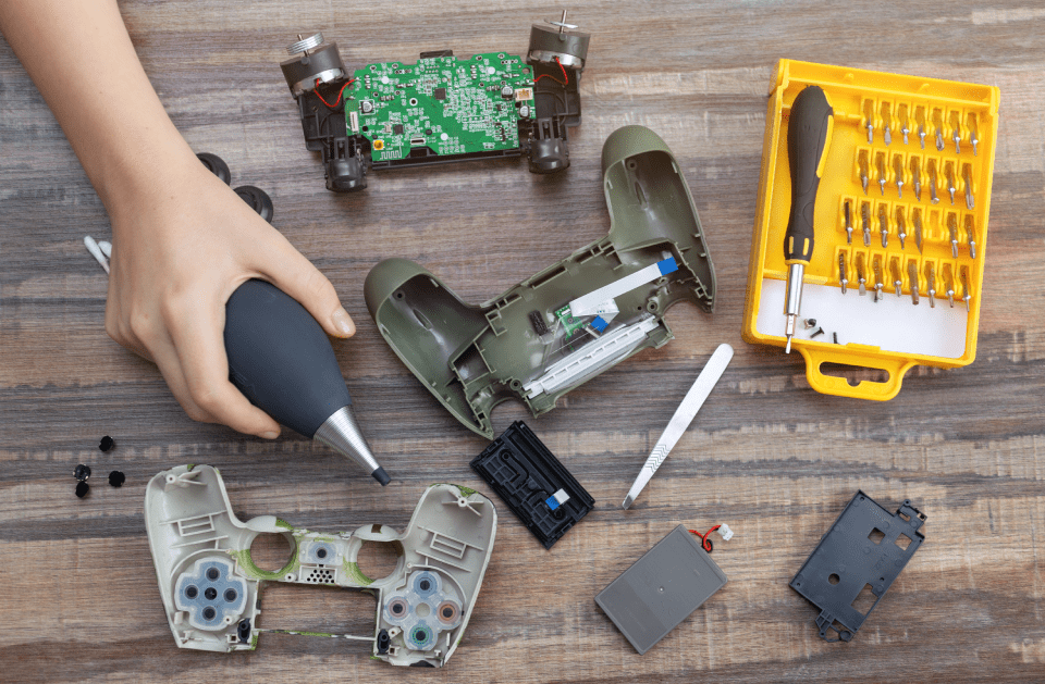 A person is cleaning a video game controller with a blower.