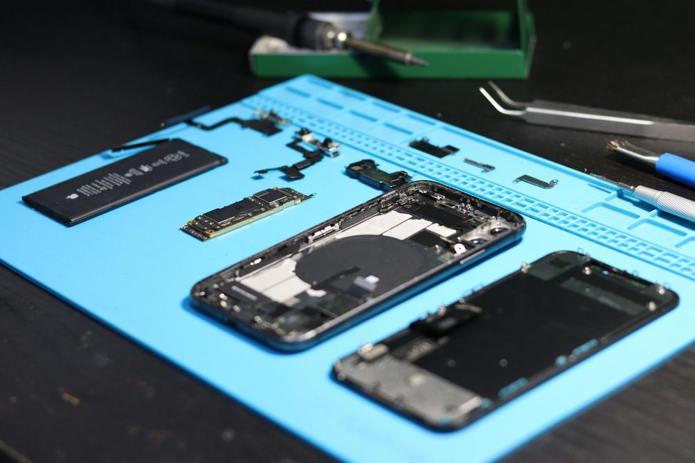 A cell phone is being repaired on a blue mat