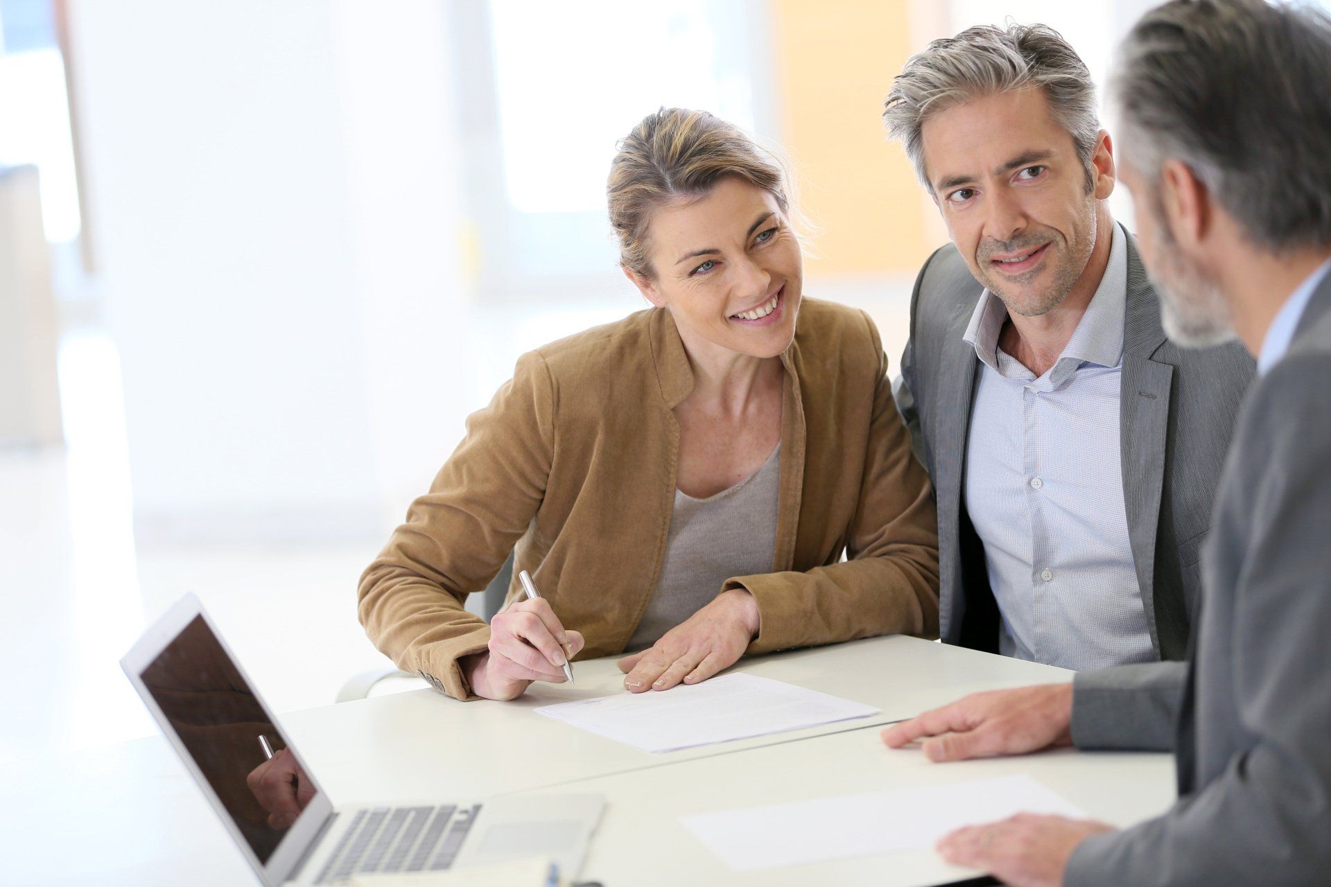 A man and a woman are sitting at a table with a laptop.