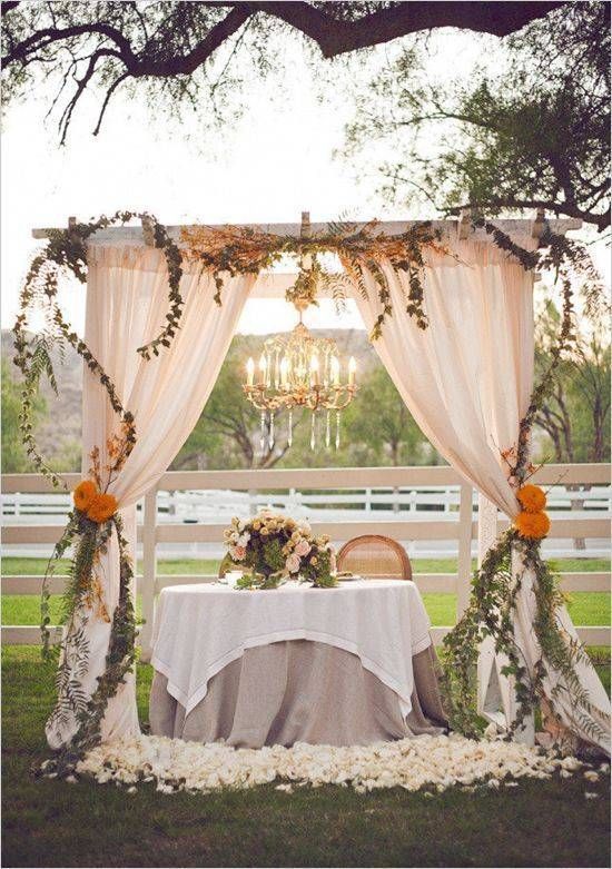 A table under a canopy with flowers and a chandelier