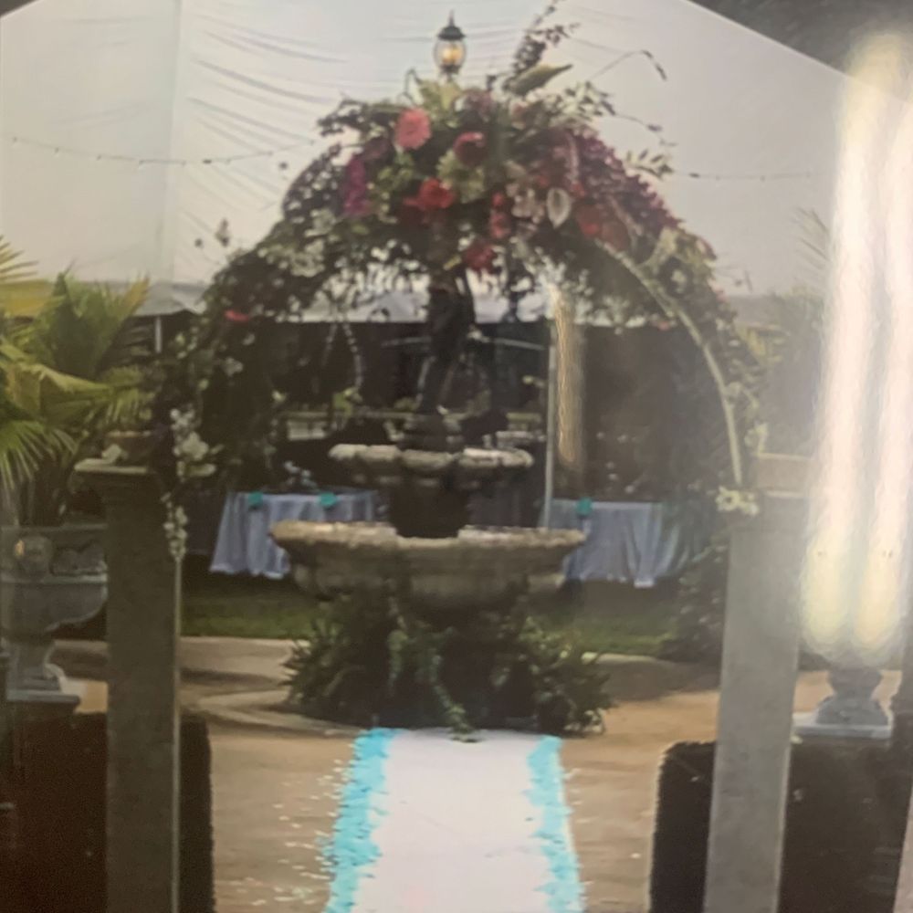 A fountain is surrounded by flowers and a white carpet
