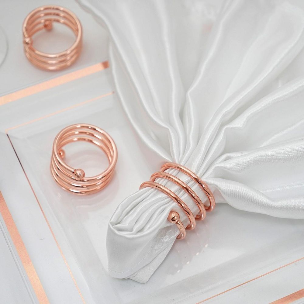 A white napkin with three rose gold napkin rings on it