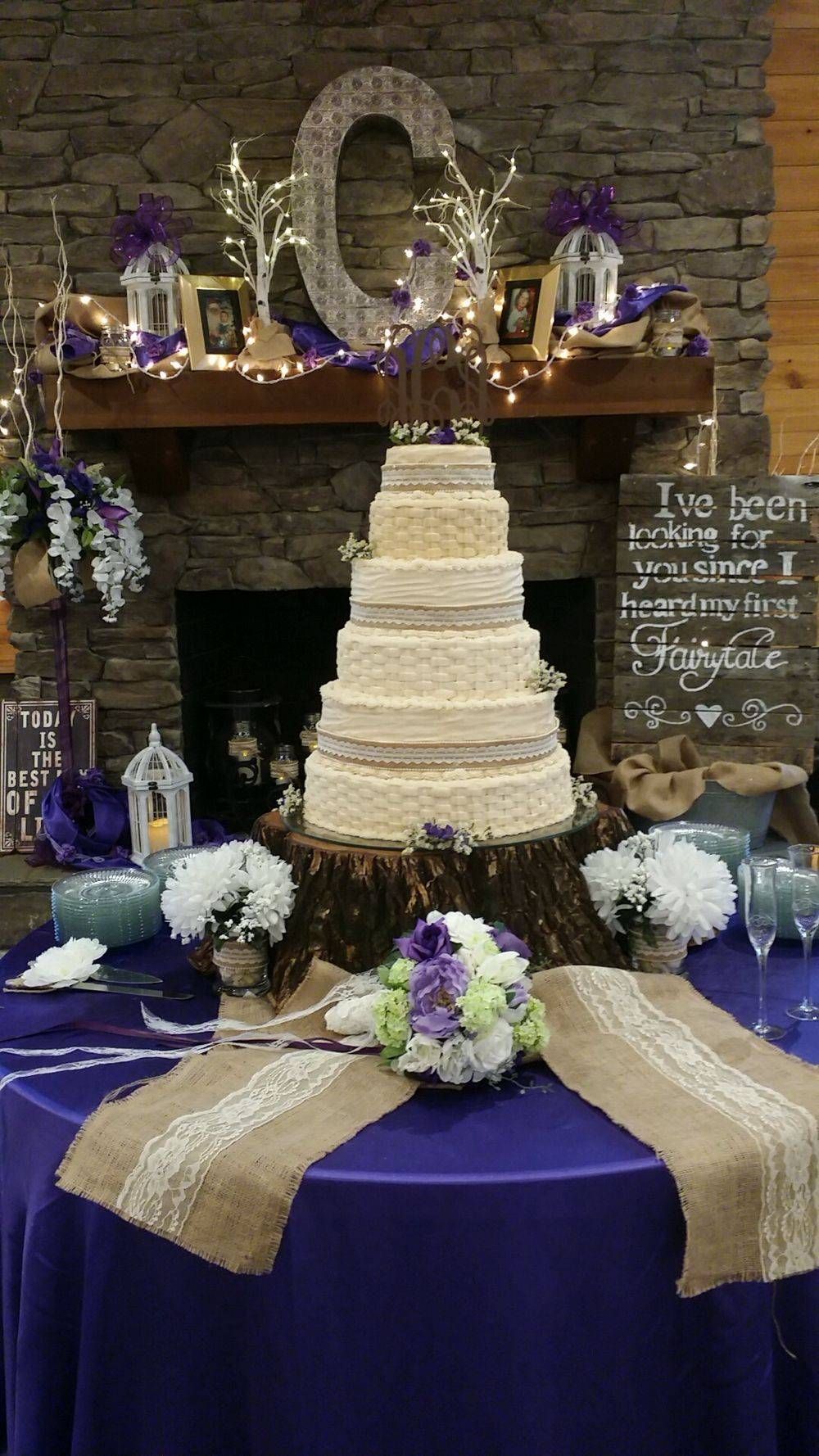 A wedding cake is sitting on top of a tree stump on a table.