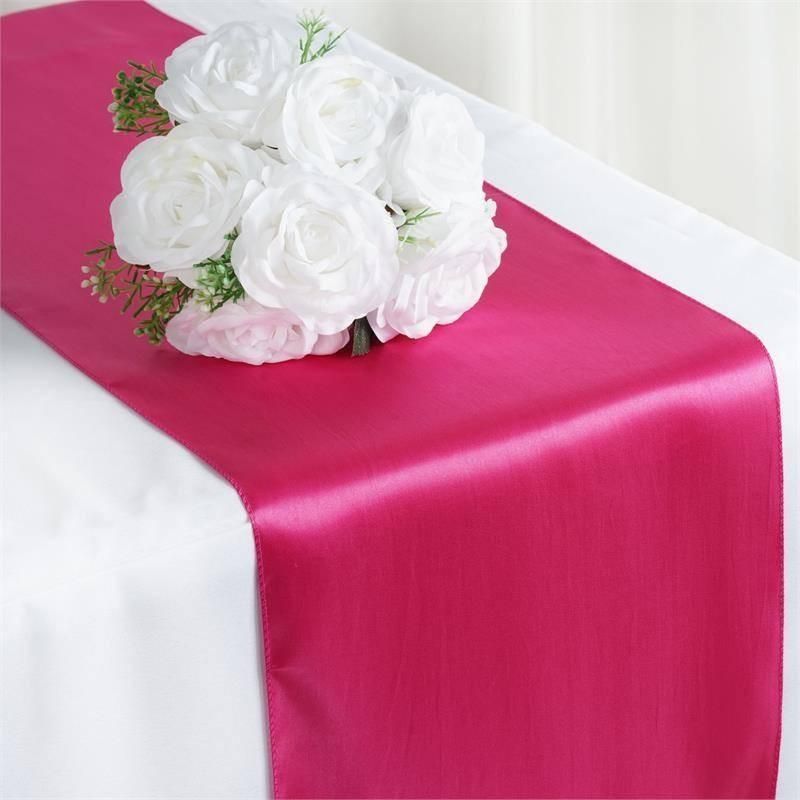 A pink table runner with white roses on it