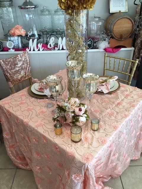 A table with a pink tablecloth and a sign that says mr. and mrs.