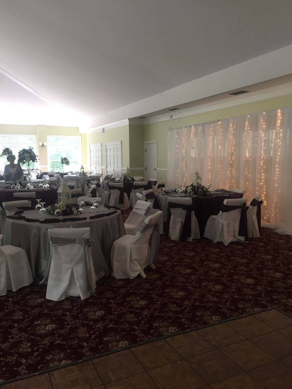 A large room with tables and chairs set up for a wedding reception.