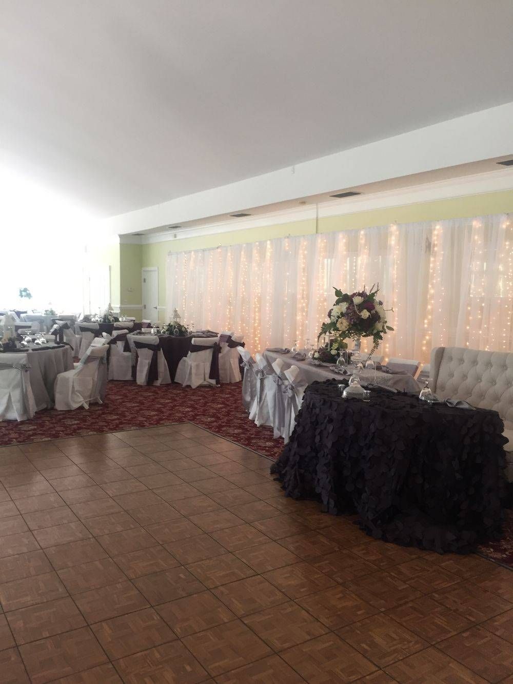 A large room with tables and chairs set up for a wedding reception.