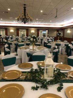 A large room with tables and chairs set up for a wedding reception