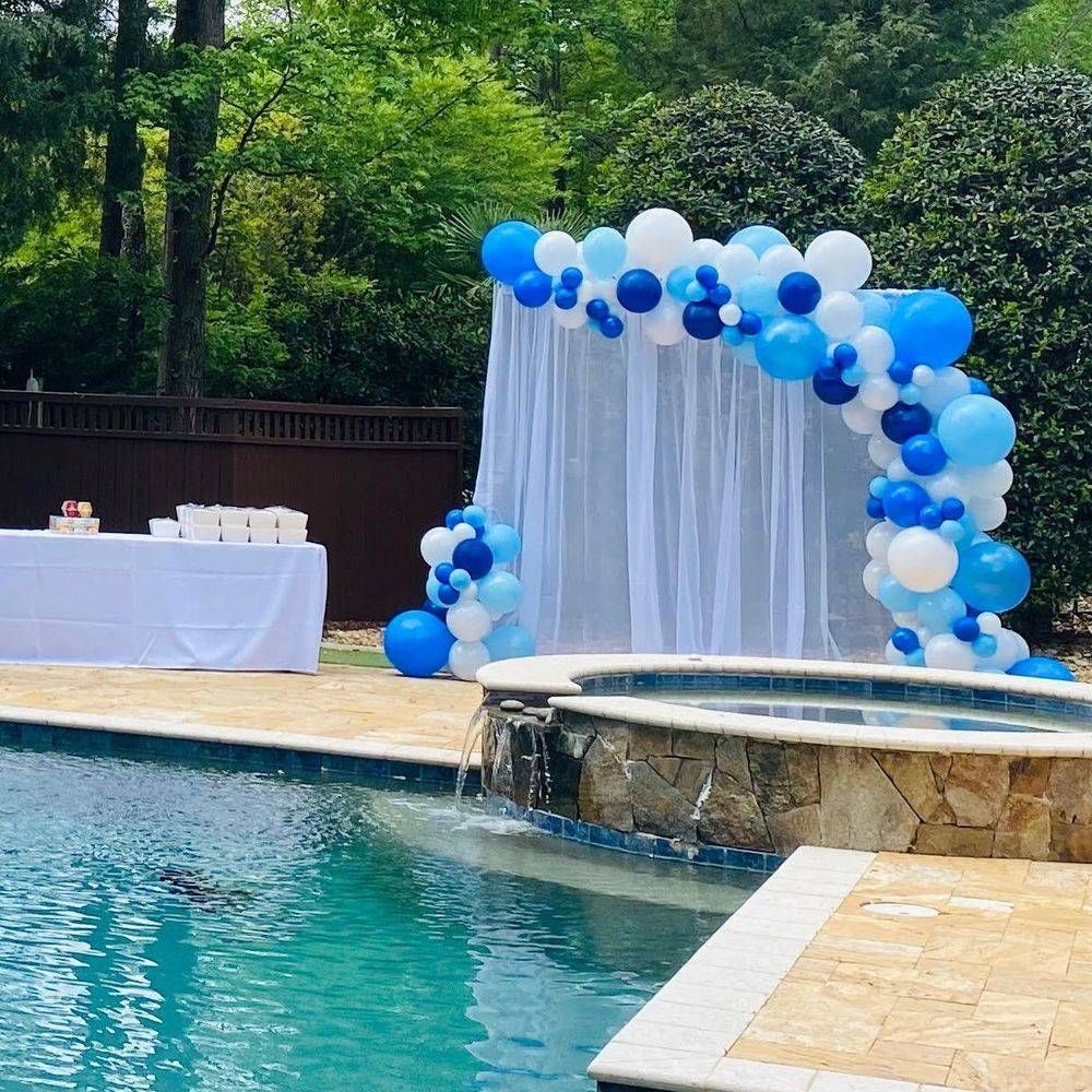 A pool decorated with blue and white balloons and a white curtain.